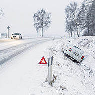 Fahrbahn im Winter und Autounfall.